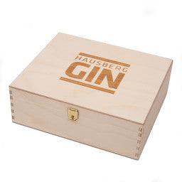 Geschlosseme Holzkiste mit Einleger für drei Gin Tasting-Flaschen mit Logo-Branding "Hausberg Gin".
Dieses Holzkistchen wird verwendet für die Hausberg Gin Tastingbox mit drei Mini-Fläschchen Gin. Geschenkset.