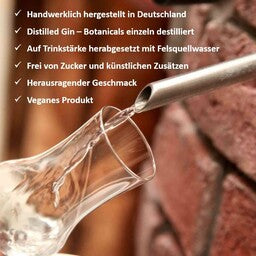 Abgebildet ist ein Glas vor dem Auslass eines Brenngeräts. Aus dem Auslass aus Edelstahl läuft Destillat in ein Probierglas.
Darüber befinden sich Hinweise zu den Produkteigenschaften der Hausberg Gins.