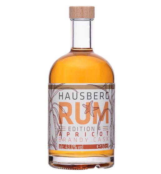 Flasche Hausberg Rum Apricot Brnady Cask mit brauner und aprikotfarbener Schrift auf weißem Etikett. Klare Glasflasche mit bernsteinfarbenem Inhalt und Holzgriff-Schraubverschluss.