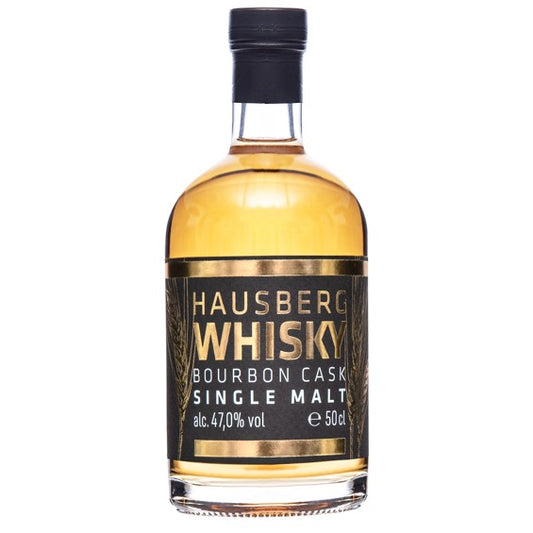 Eine Flasche Hausberg Whisky Single Malt aus dem Ex-Bourbon-Fass mit 47% vol. Alkohol und 50cl Inhalt. Schwarzes Etikett mit goldener Prägung und weißer Schrift. Die Flasche ist verschlossen mit einer edlen schwarzen Schrumpfkapsel. Die Flasche wirkt sehr wertig und edel wie ein ideales Geschenk für Whiskyliebhaber und Sammler.